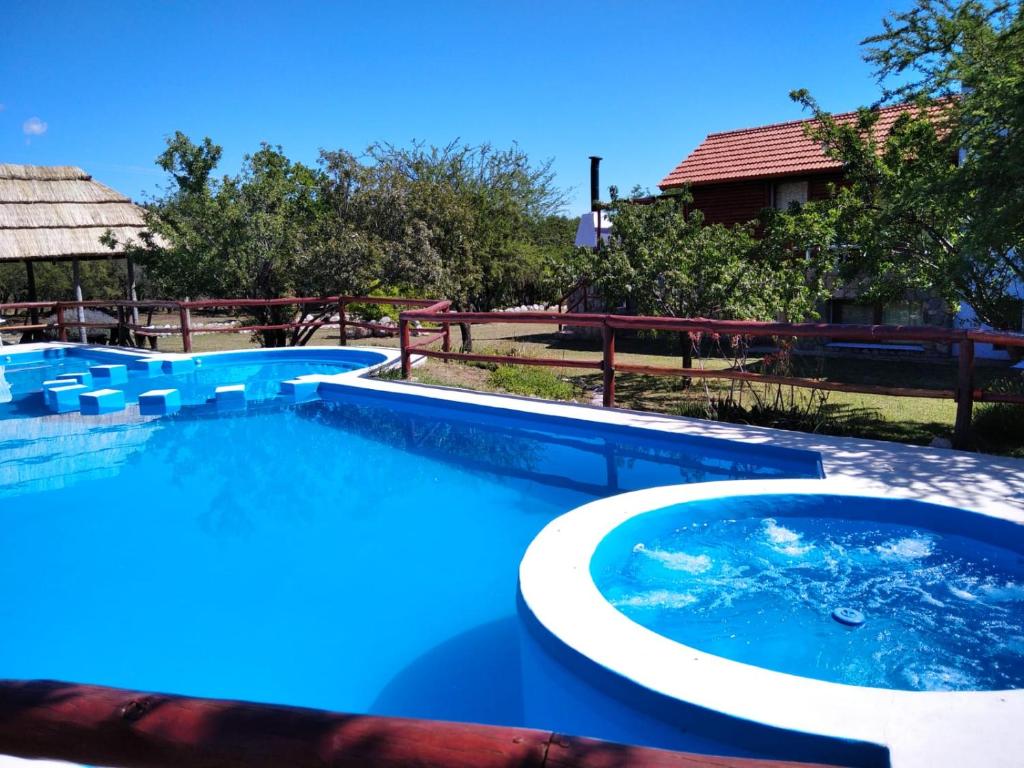 a large swimming pool with blue water in a yard at Cabañas Yanasuy in Merlo