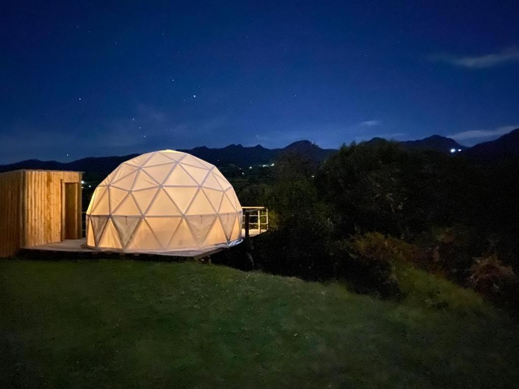 a large dome building on a field at night at La Meca Glamping in Guasca