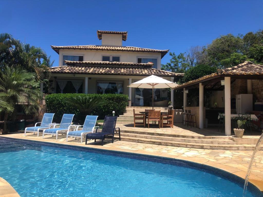 a villa with a swimming pool and chairs and a house at Casa em Búzios in Búzios