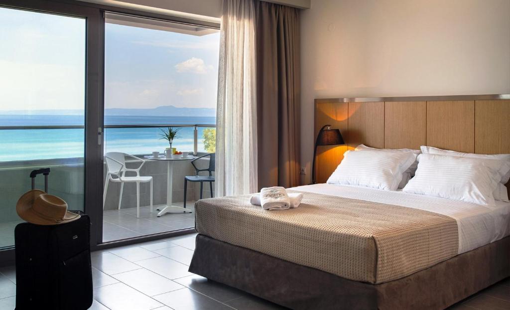 a bedroom with a bed and a view of the ocean at Ostria Sea Side Hotel in Hanioti