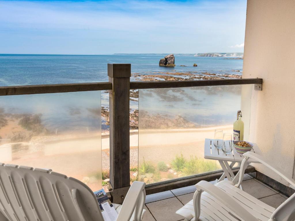 een balkon met stoelen en een tafel en uitzicht op het strand bij 3 Thurlestone Rock in Kingsbridge