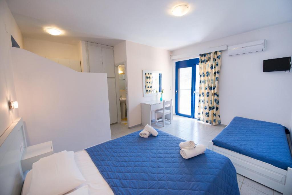 a bedroom with two beds with blue sheets and towels at Akroyiali Resort in Vasiliki