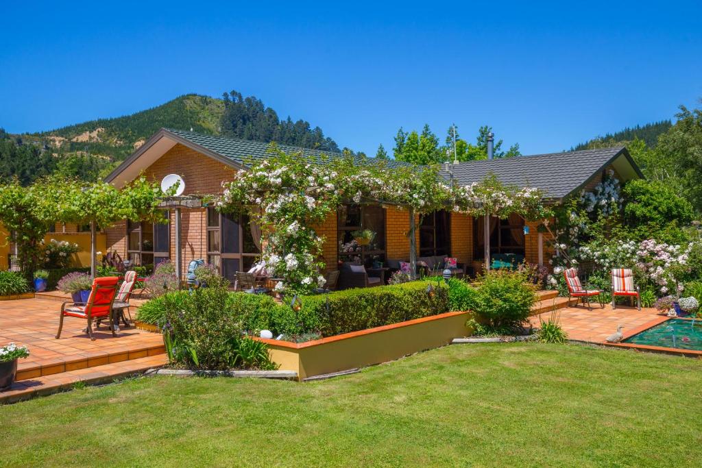 ein Haus mit einer Terrasse und einem Garten mit Blumen in der Unterkunft Picton Country Hideaway in Picton
