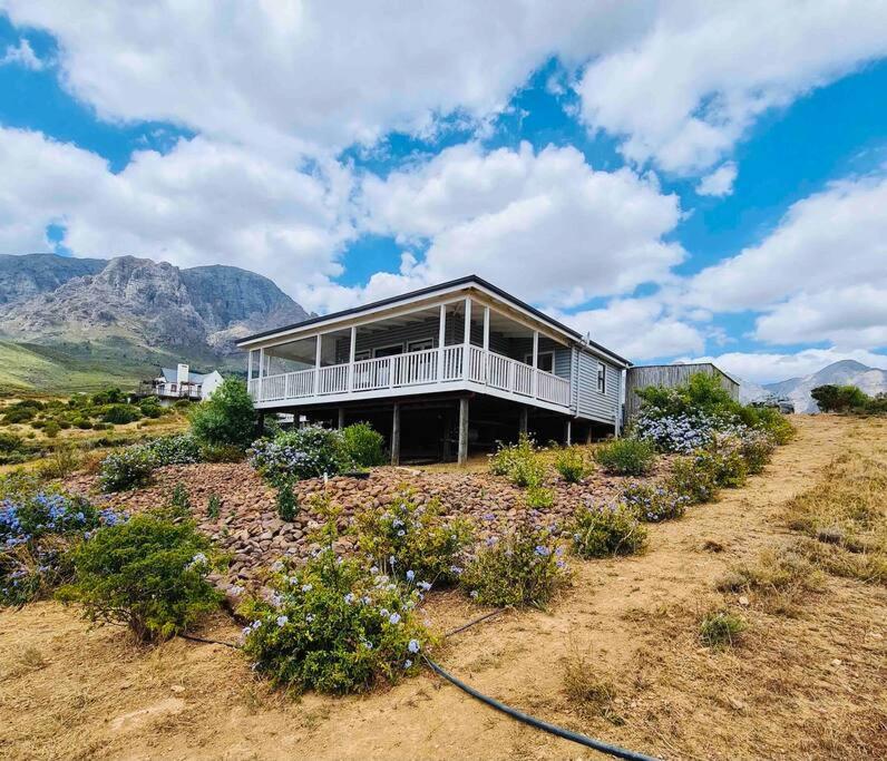 a house sitting on top of a field with mountains at Exquisite chalet on private nature reserve in Wolseley