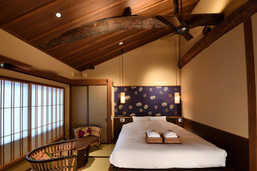 a bedroom with a bed in a room with wooden ceilings at Muromachi Yutone Kyokoyado in Kyoto