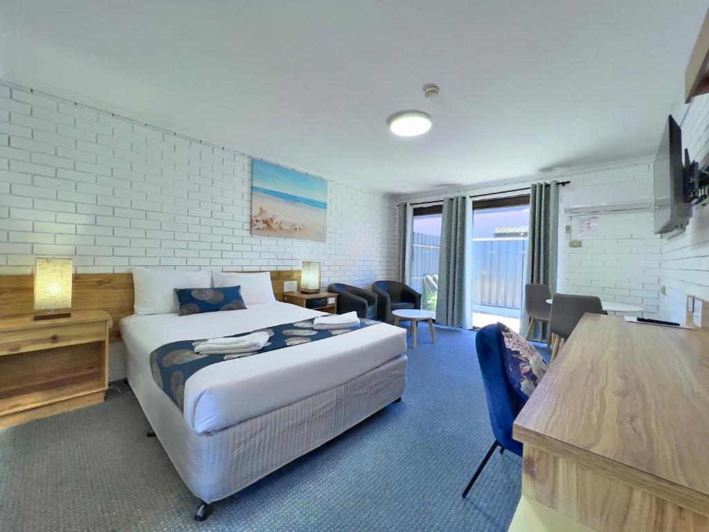 a hotel room with a bed and a desk and chairs at Albury Garden Court Motel in Albury