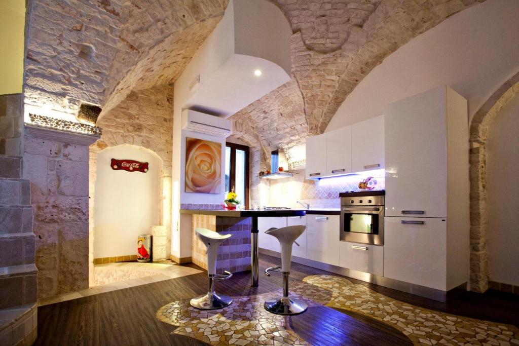 kuchnia z białymi szafkami i kamienną ścianą w obiekcie L'Angolo di Gaudì, casa Milà w mieście Putignano