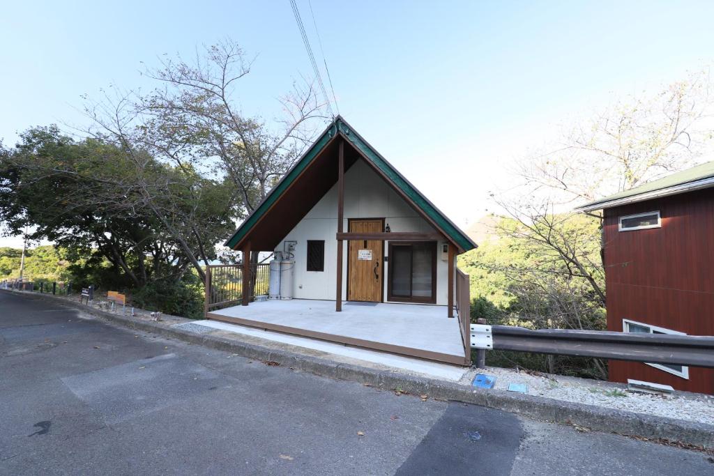 uma pequena casa sentada ao lado de uma estrada em 白浜ホープヒルズ　N-33号棟 em Shirahama