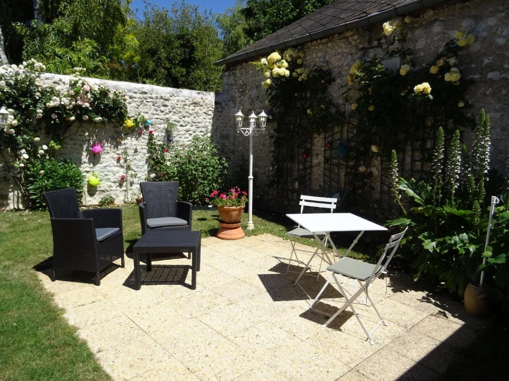 a patio with chairs and a table in a garden at Gîte Beaugency, 3 pièces, 2 personnes - FR-1-590-196 in Beaugency