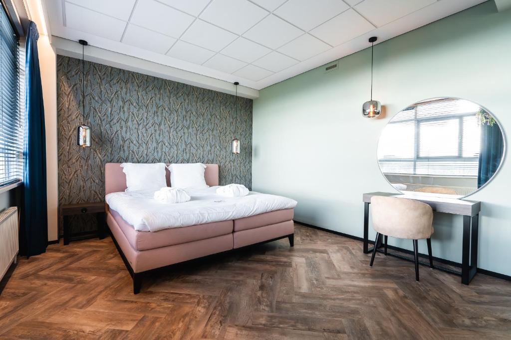 a bedroom with a bed and a table and a chair at Onderwijshotel De Rooi Pannen Eindhoven in Eindhoven