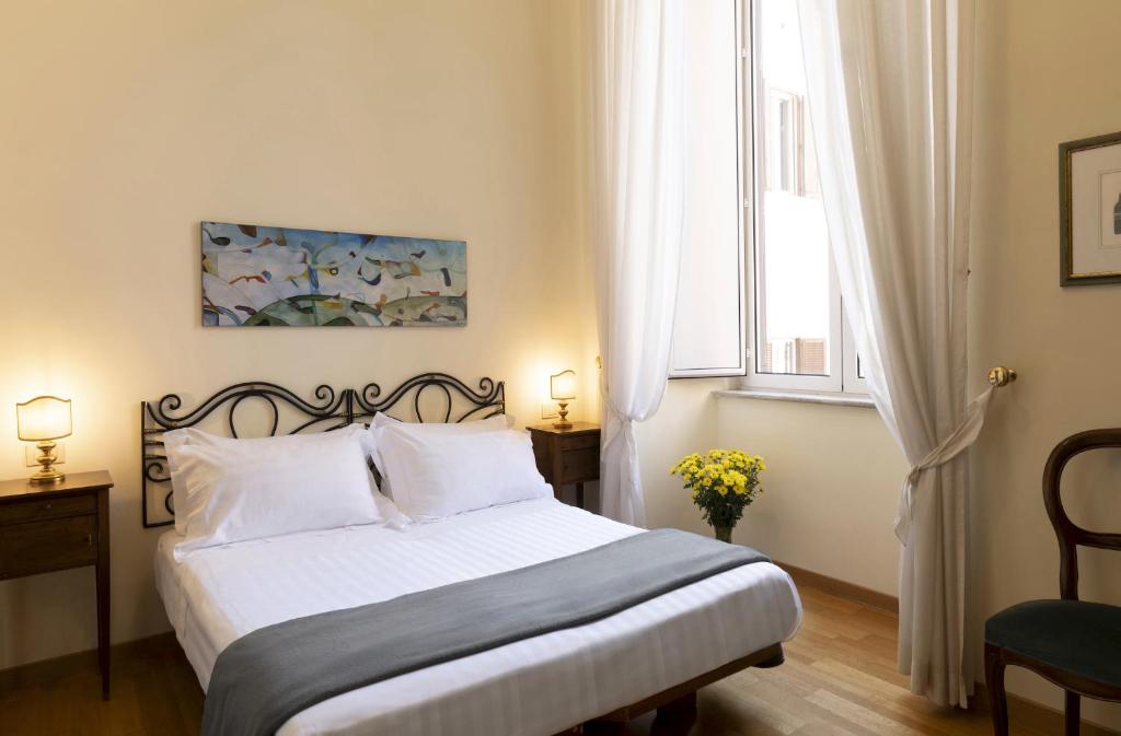 een slaapkamer met een bed met witte lakens en een raam bij All'obelisco in Rome
