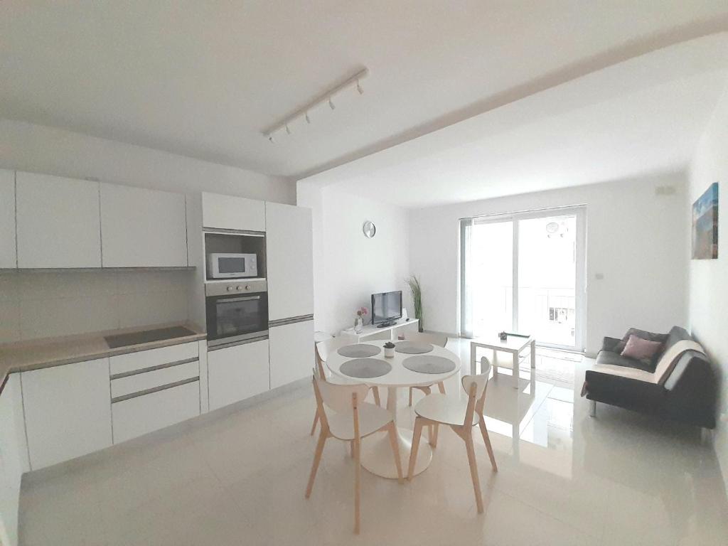 Il comprend une cuisine et un salon avec une table et des chaises. dans l'établissement Sliema Ferries Apartment, à Sliema