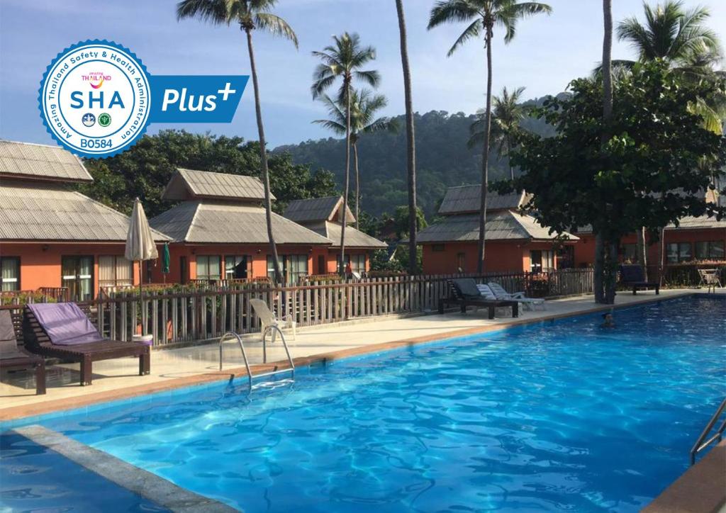 a swimming pool at a resort with a sign that says plus at Lanta Cottage - SHA Plus in Ko Lanta