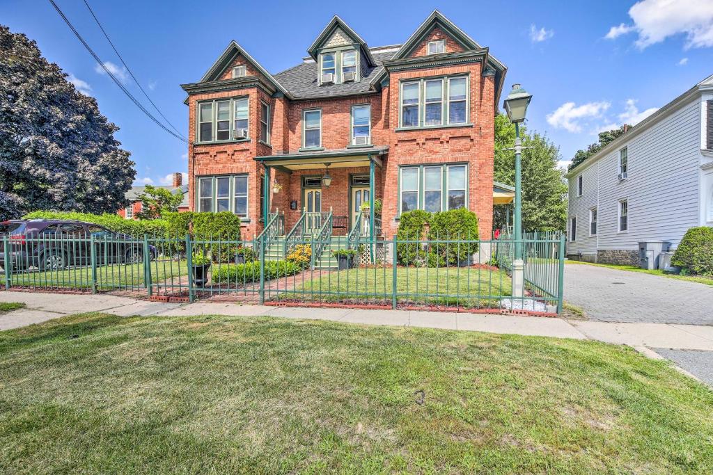 a brick house with a gate in front of a yard at Historic Apartment - Half Mi to Lake Champlain! in Plattsburgh