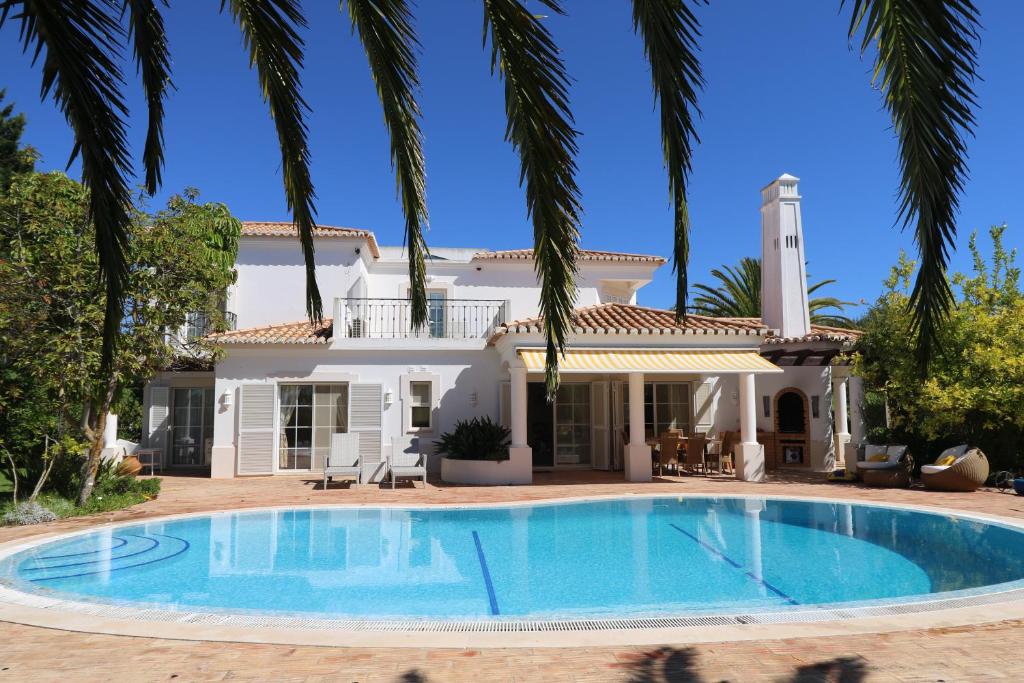 una gran piscina frente a una casa con palmeras en Peaceful 4BR villa on Gramacho golf resort w/ private pool, en Lagoa