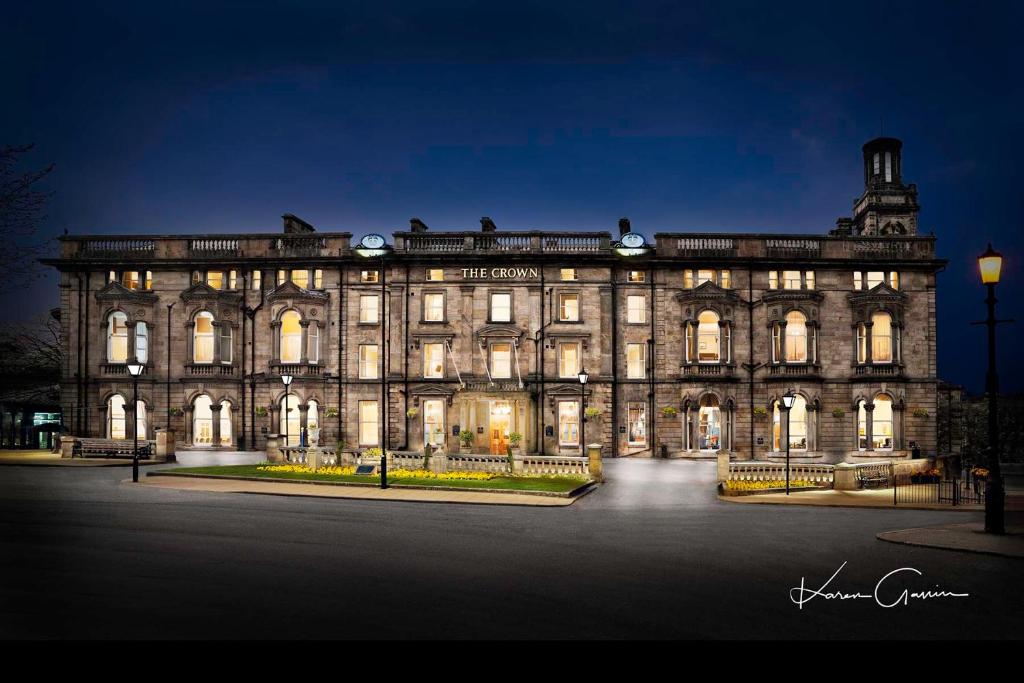 un gran edificio de piedra por la noche con luces encendidas en The Crown Hotel en Harrogate