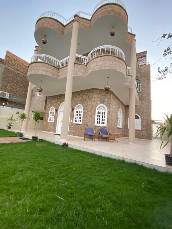 une grande maison avec une pelouse devant elle dans l'établissement Nile palace villa, à Louxor