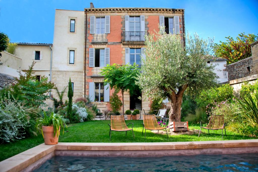 ein Haus mit Stühlen und einem Pool davor in der Unterkunft La Maison Rouge d'Uzes B&B in Uzès