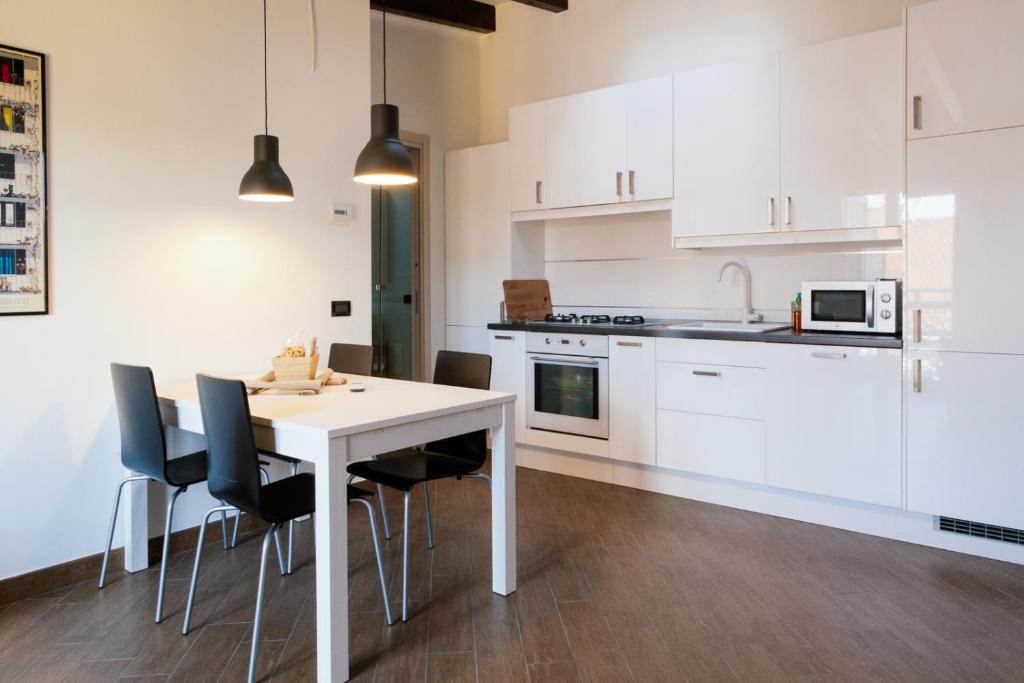 - une cuisine avec des placards blancs, une table et des chaises dans l'établissement IMHOME - Ripamonti, à Milan