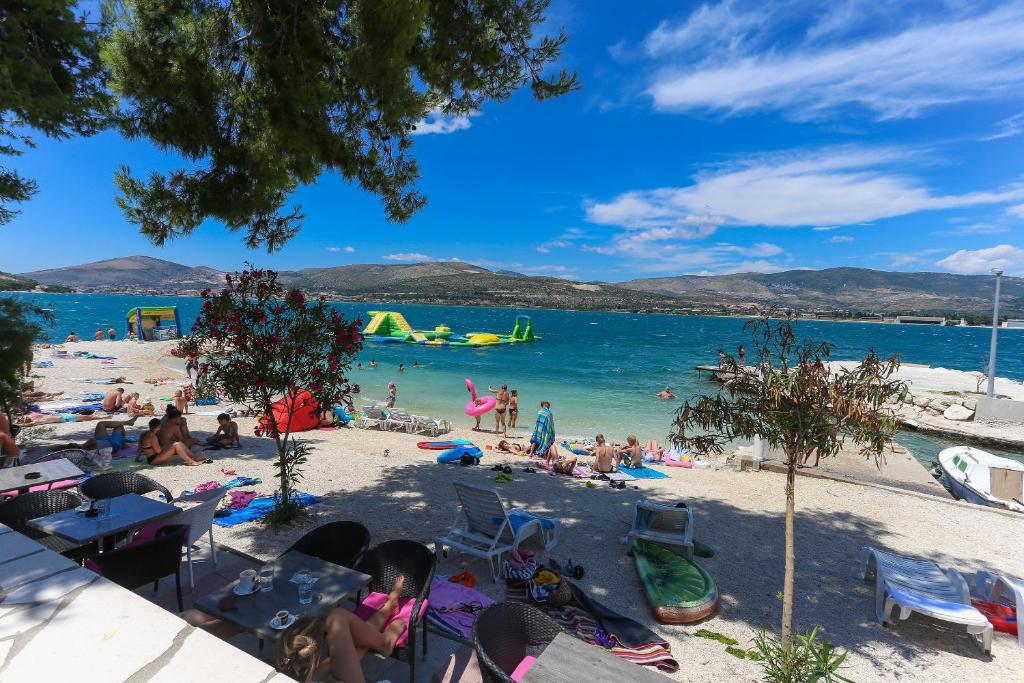 um grupo de pessoas em uma praia com um corpo de água em Apartments and Rooms Villa Niko em Trogir