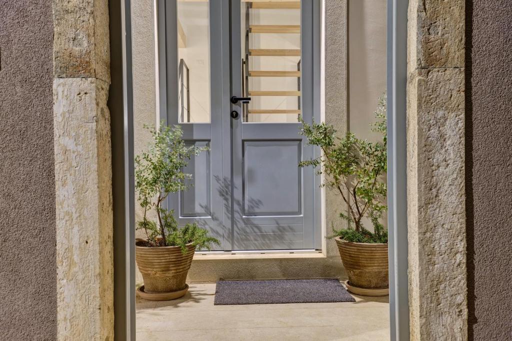 une porte ouverte avec des plantes en pot sur une terrasse couverte dans l'établissement Casa Santa Maria Vacation House, à Mali Lošinj