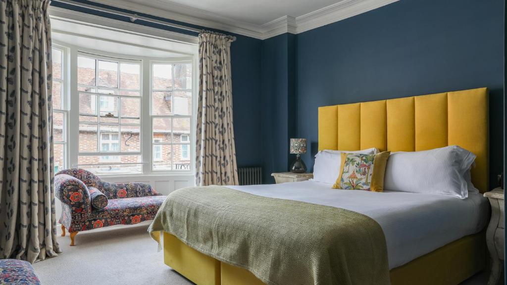 a bedroom with a bed and a chair and a window at The Bear Hotel in Wareham