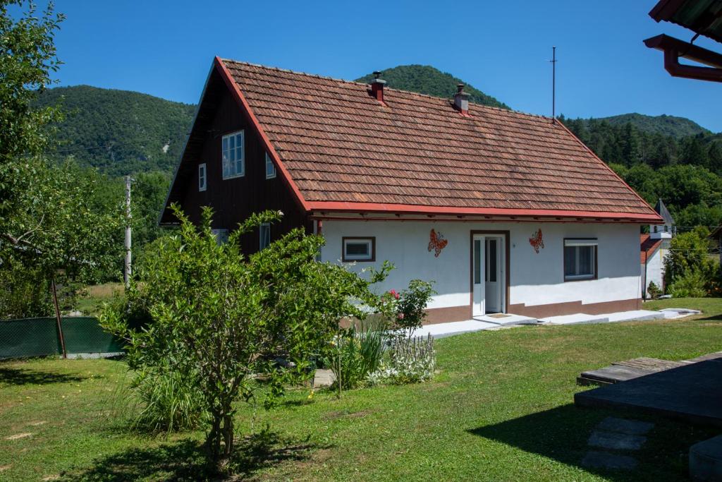 una casa en blanco y negro con techo rojo en Holiday Home Colnar en Brod na Kupi