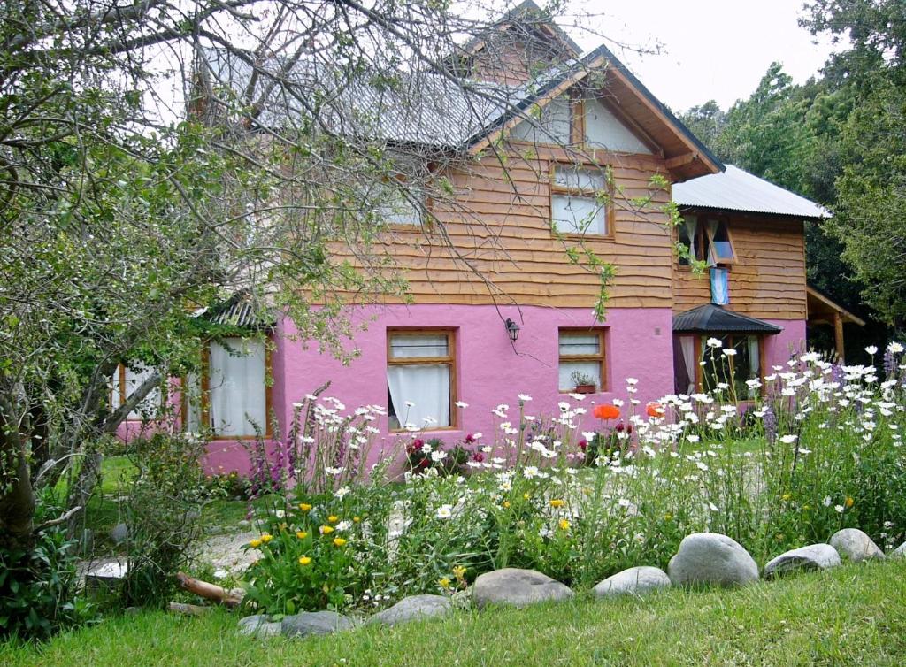 una casa rosa con flores delante en Verde Sol en San Carlos de Bariloche