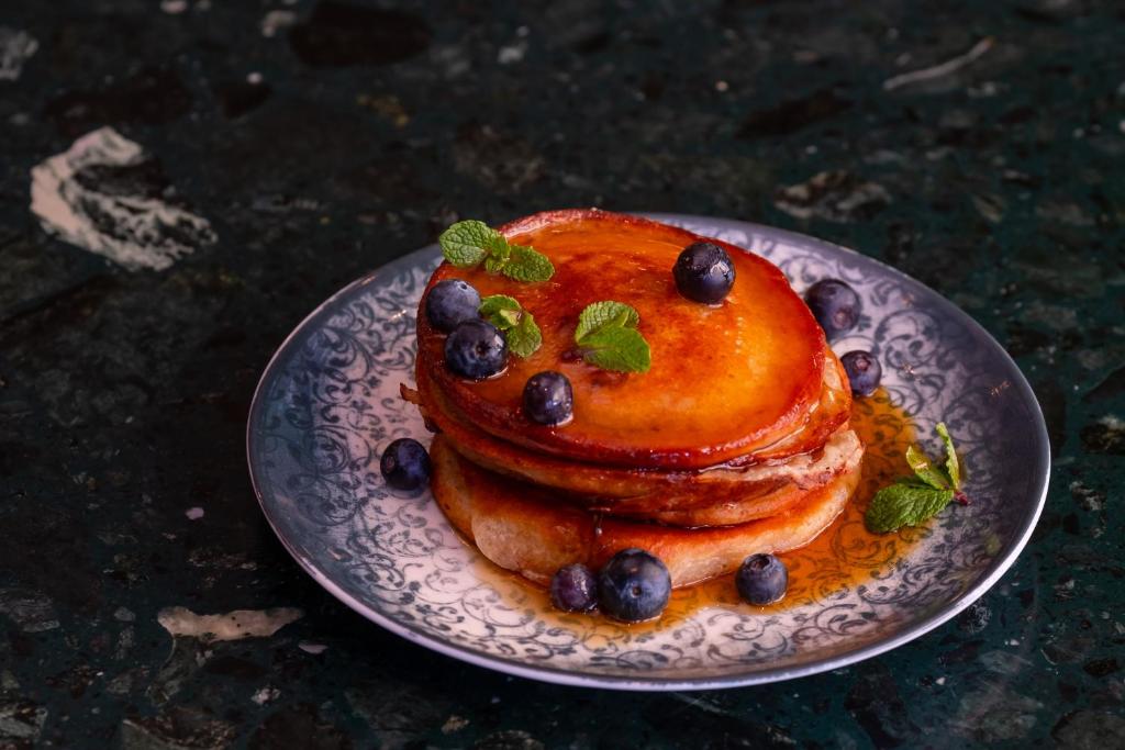 a plate with a stack of pancakes with blueberries and mint at Hotel Hasselbacken in Stockholm