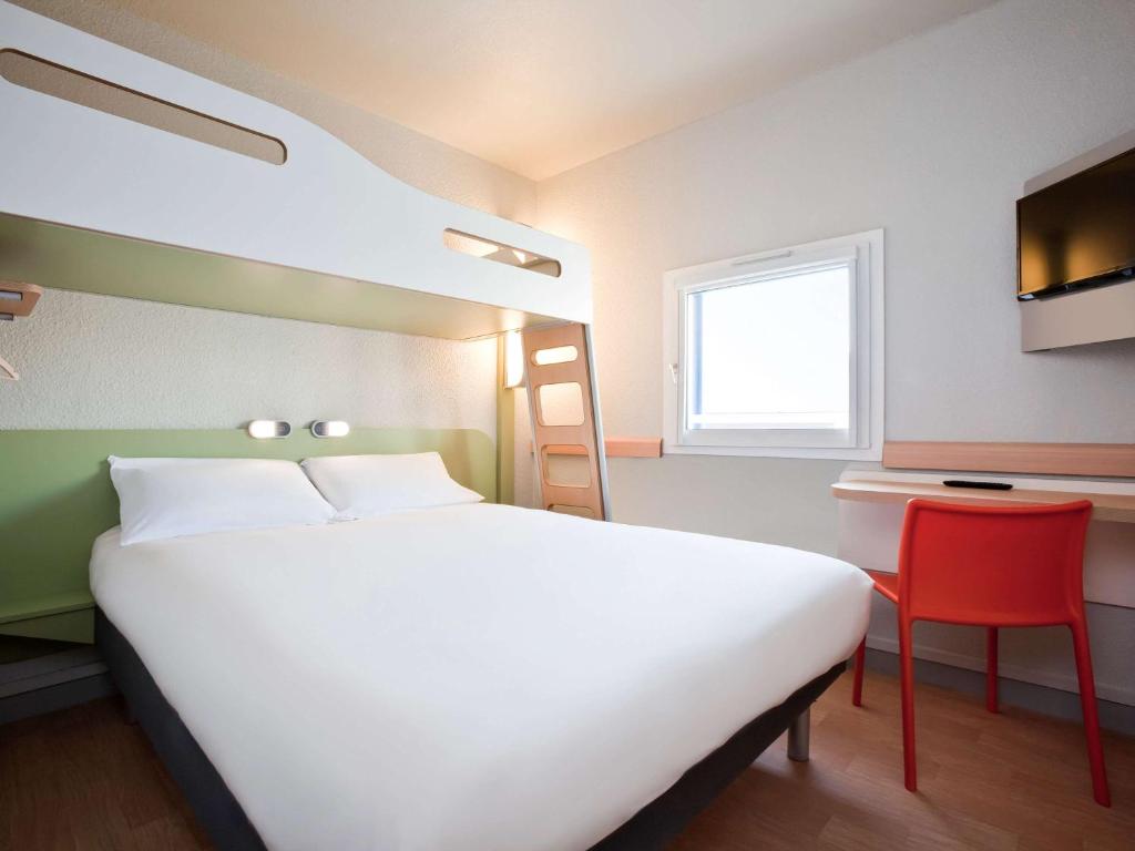 - une chambre avec un grand lit blanc et une chaise rouge dans l'établissement ibis budget Pontault Combault RN4 Marne La Vallée, à Pontault-Combault