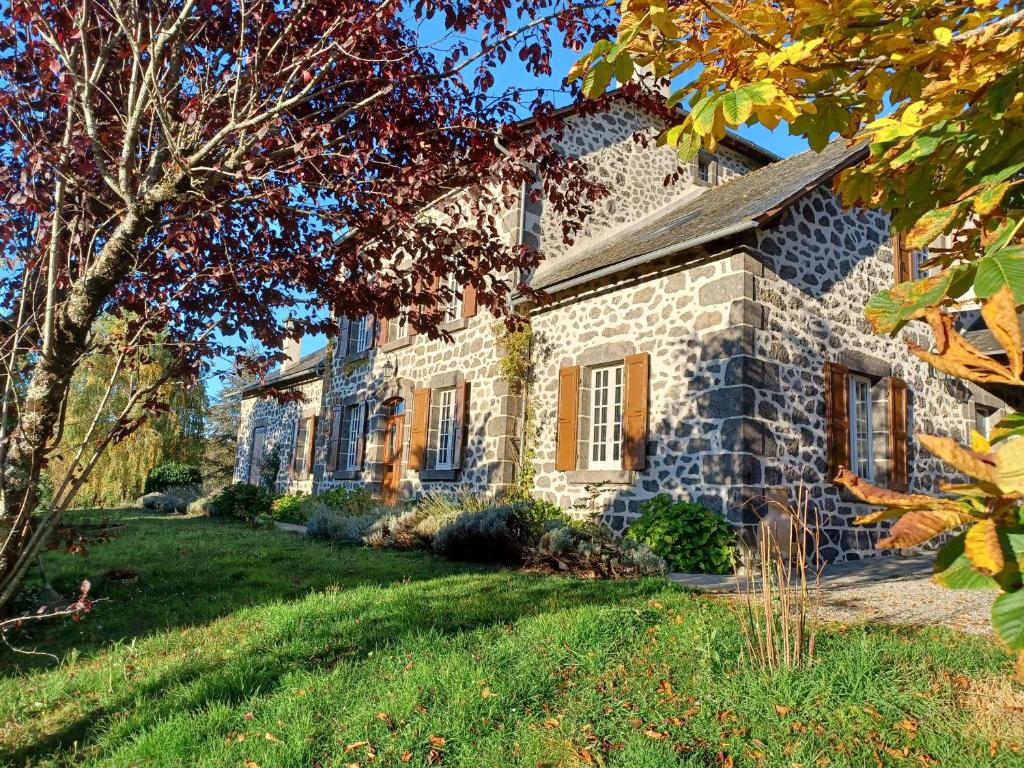 une maison en pierre avec une cour devant elle dans l'établissement La Grange de Lily, à Vic-sur-Cère