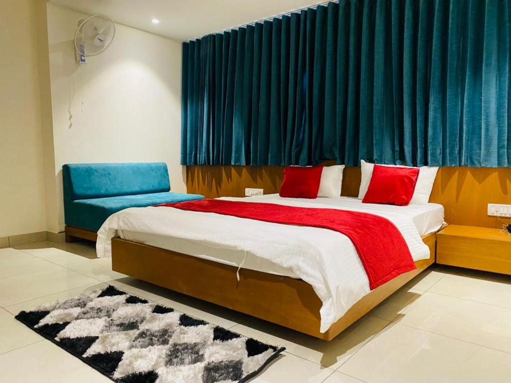 a bedroom with a large bed and a blue curtain at Hotel Prime in Gandhinagar