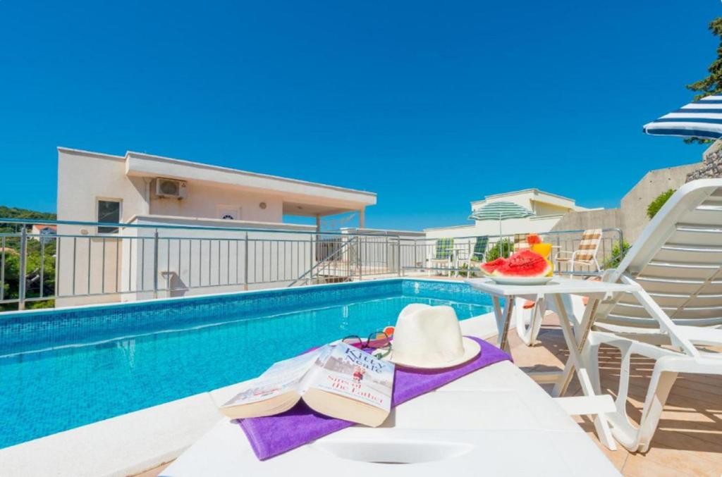 a swimming pool with a table and chairs next to a pool at Villa Borna Apartments in Dubrovnik
