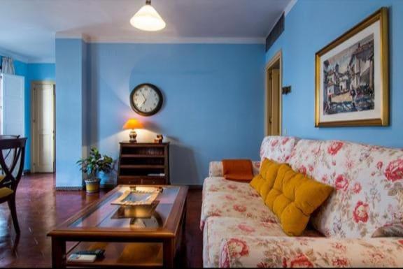 salon z kanapą i zegarem na ścianie w obiekcie Apartamento en un dormitorio en Plaza Alfaro w Sewilli