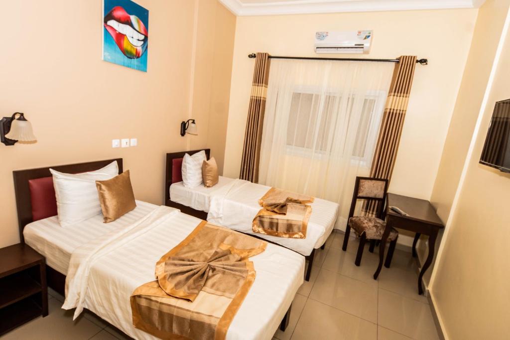 a hotel room with two beds and a desk at ISIS Hôtel in Yaoundé