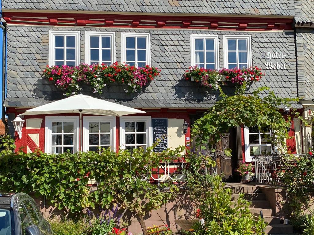 ein Haus mit Blumen in den Fenstern und einem Regenschirm in der Unterkunft Hotel Weber in Amöneburg