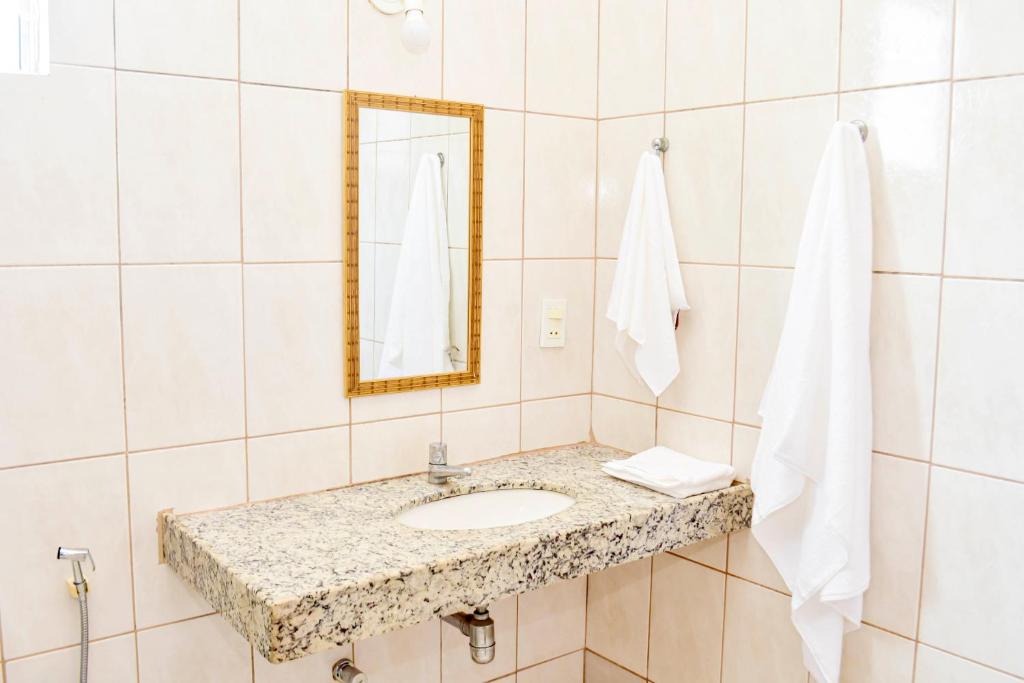 een badkamer met een wastafel en een spiegel bij Pousada Flamboyant in Olímpia