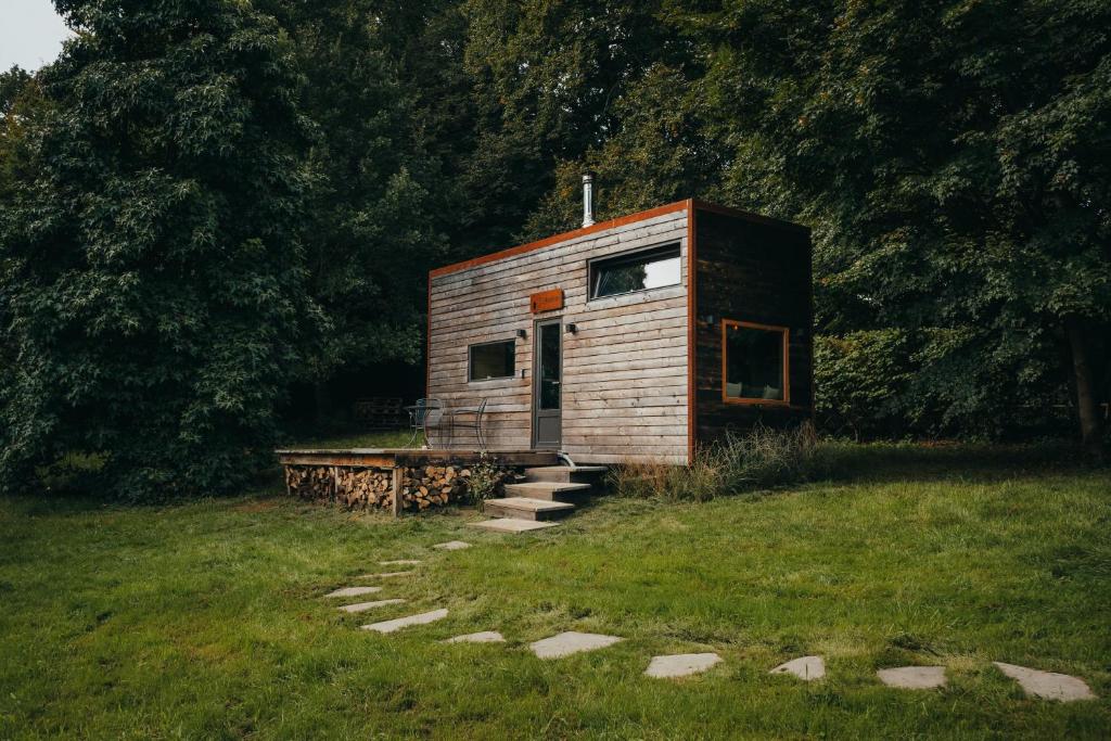 mały drewniany domek na polu trawy w obiekcie Tiny House Célestine By Ernesst w mieście Overijse
