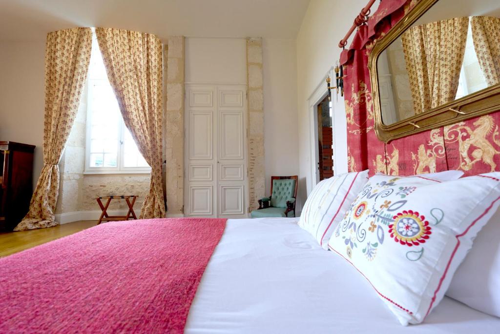 - une chambre avec un grand lit et une tête de lit rouge dans l'établissement Château de Mazelières, à Espiens