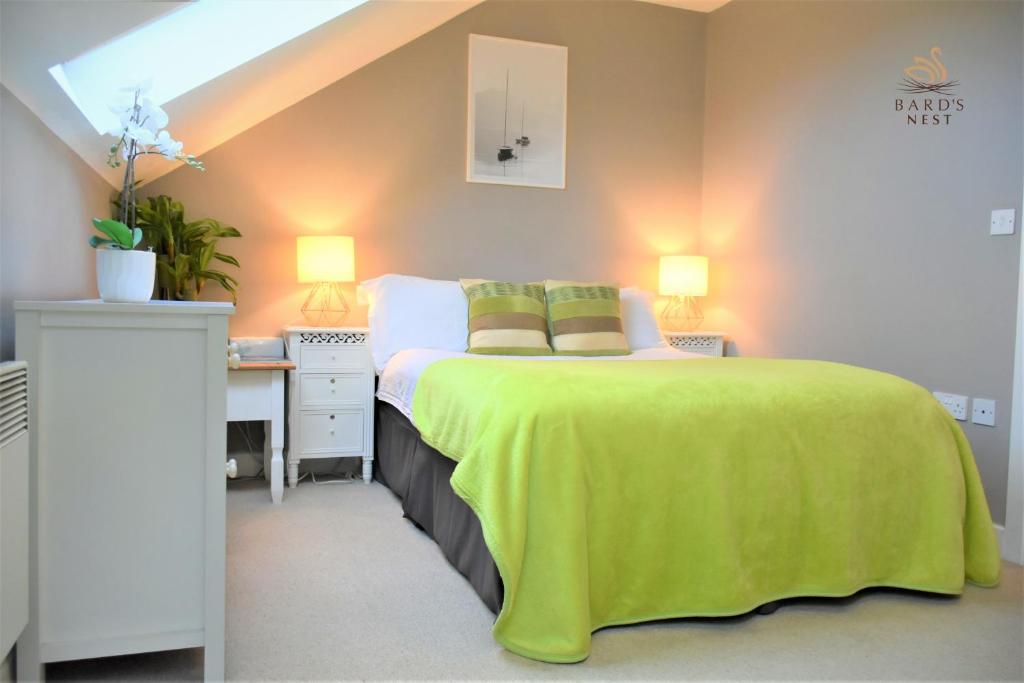 Un dormitorio con una cama con una manta verde. en Bard's Nest, Crucible Apartment, FREE private parking, 3 mins walk to Birthplace, en Stratford-upon-Avon