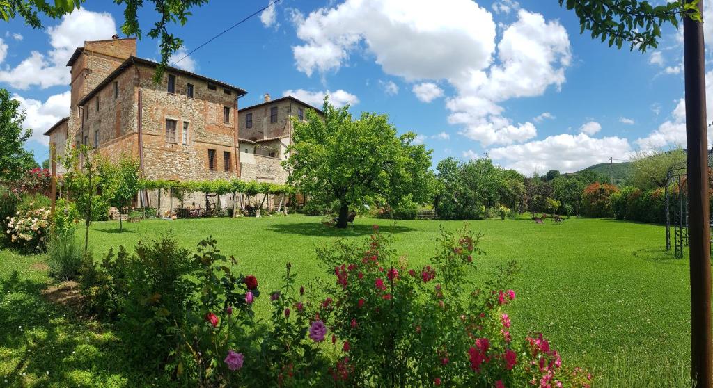 un viejo edificio de ladrillo en un campo con flores en Agriturismo Abbazia Sette Frati a casa di Sara, en Pietrafitta