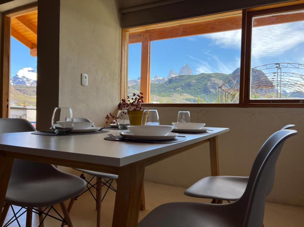 a dining room table with chairs and a large window at Chaltén Mountain Lofts 2 in El Chalten