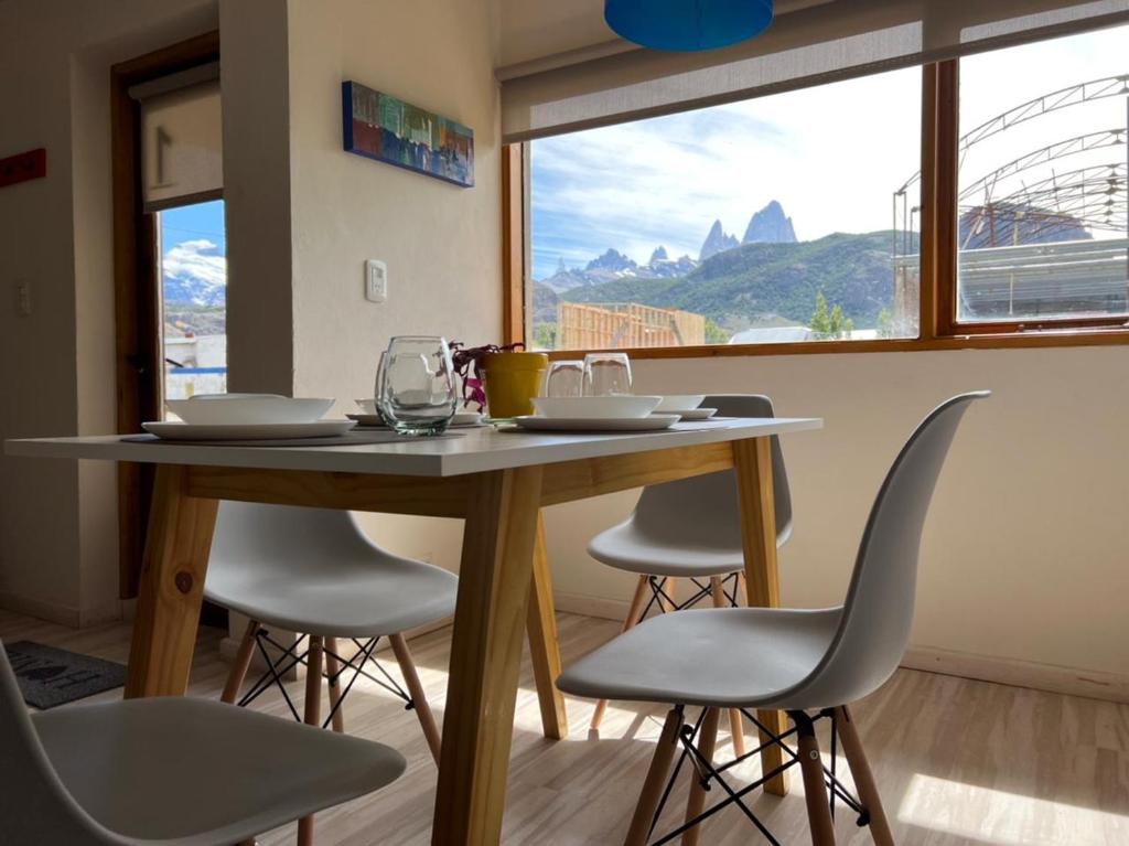 a dining room table with chairs and a large window at Chaltén Mountain Lofts 1 in El Chalten