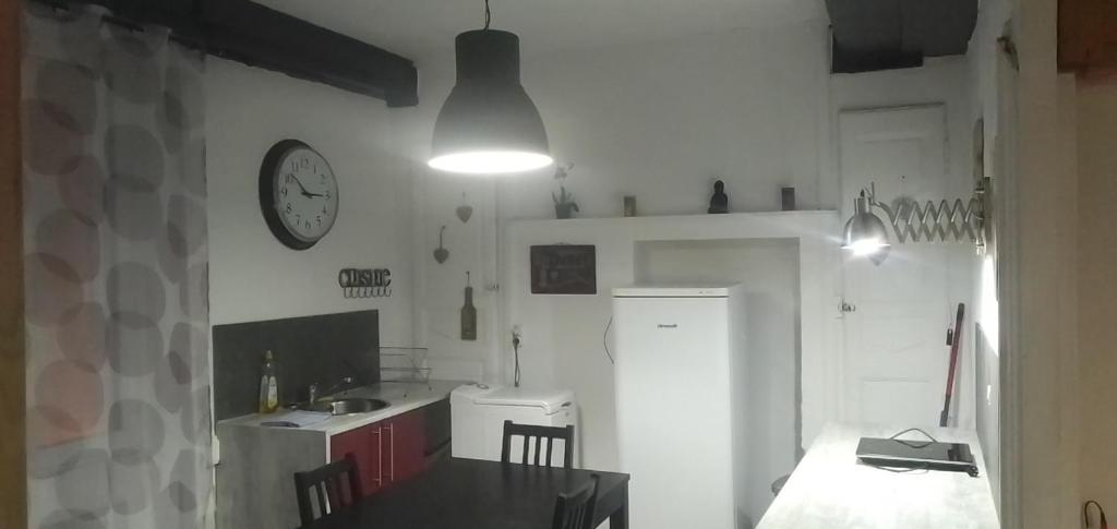 a kitchen with a table and a clock on the wall at Au coeur de la Durolle in Thiers