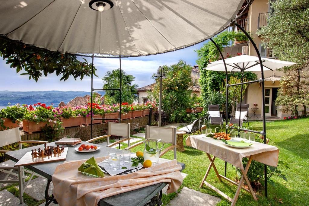 eine Terrasse mit Tischen, Stühlen und einem Sonnenschirm in der Unterkunft "Luisa's Smile" in Guarene