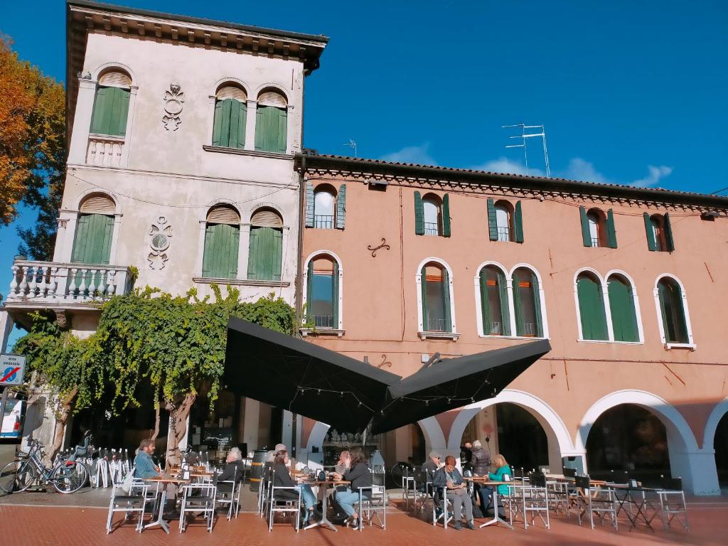 un groupe de personnes assises à des tables devant un bâtiment dans l'établissement Ca' Palazzo, à Mestre