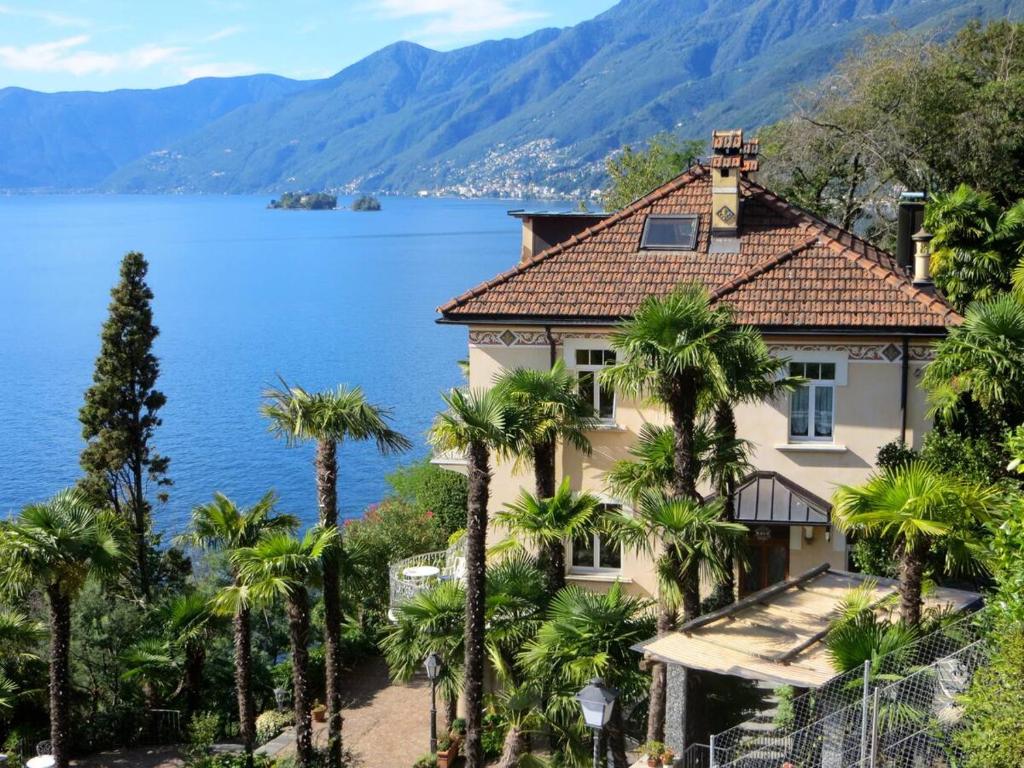 a house with palm trees in front of a lake at Ascona: Casa Rivabella in Ascona