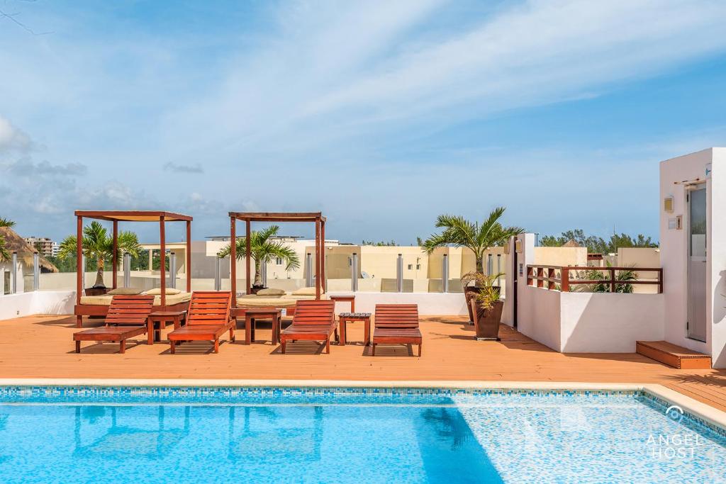 - une piscine avec des chaises et une table à côté de la piscine dans l'établissement Casa del Mar by Stella Rentals, à Playa del Carmen