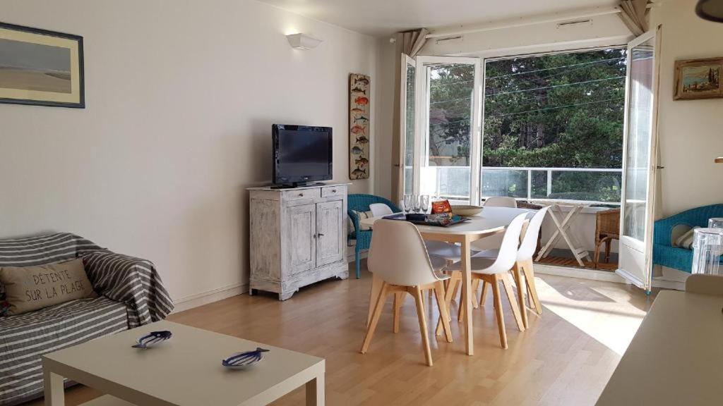 un salon avec une table, des chaises et une télévision dans l'établissement Grand appartement traversant 3 ch hyper-centre+Parking privé., à Le Touquet-Paris-Plage