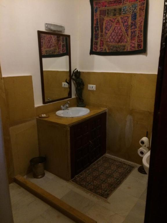 Killa Bhawan Lodge في جيلسامر: حمام مع حوض ومرآة